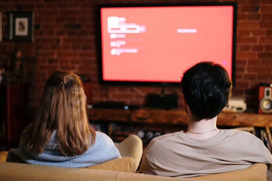 Couple on a sofa facing a large TV in a brick-walled living room